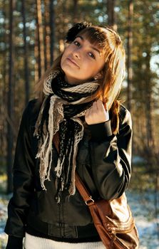 Young beautiful girl in black jacket on background wood