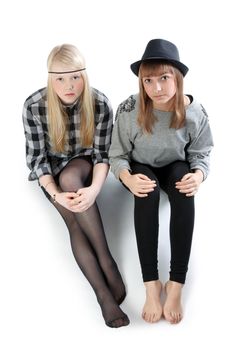 Two beautiful young girls sit on floor