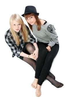 Two beautiful young girls sit on floor