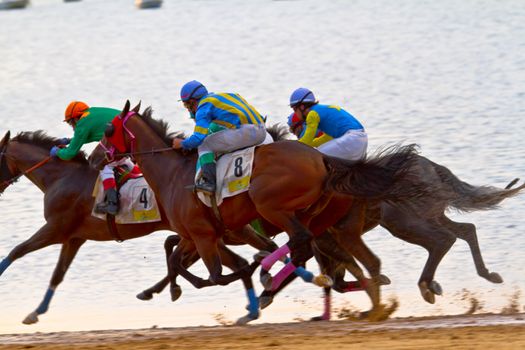 SANLUCAR DE BARRAMEDA, CADIZ, SPAIN - AUGUST 11: Unidentified riders race horses on Sanlucar de Barrameda beach on August 11, 2011 in Sanlucar de Barrameda, Cadiz, Spain.