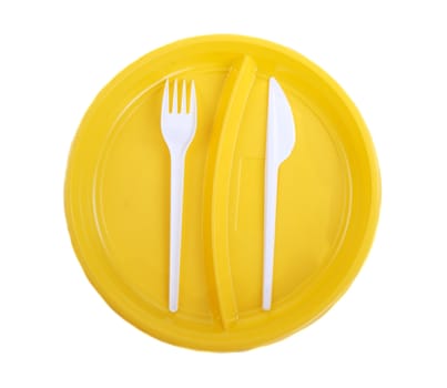 Yellow plastic plate, fork and knife on white background