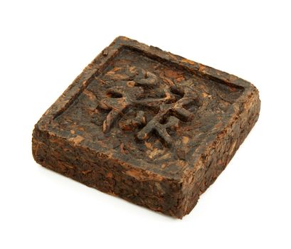 Pressed briquette of green tea with hieroglyphic on white background