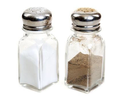 Glass saltcellar and pepper shaker on white background