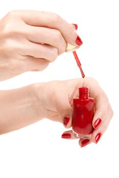 Women's hands with a bottle of red nail polish
