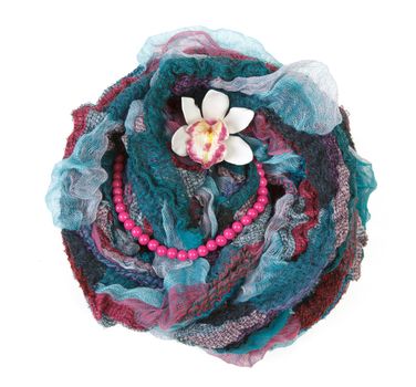 Varicoloured scarf is put with necklace around and flower on white background
