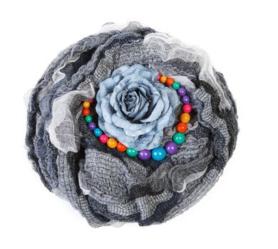Varicoloured scarf is put with necklace around and flower on white background