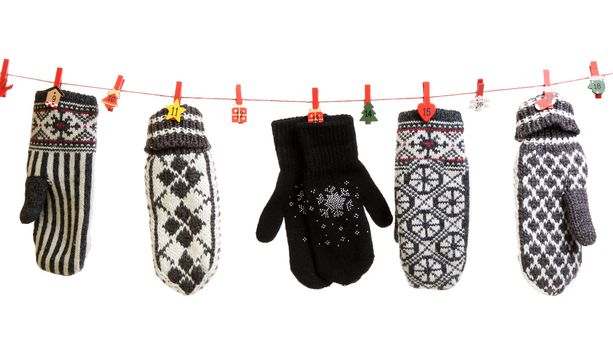 Winter knitted gloves hang on the Christmas lights in the clothes pins