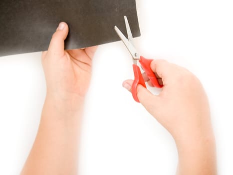Children's hands with scissors cut a paper