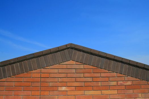 Brick roof peak over clear blue sky.
