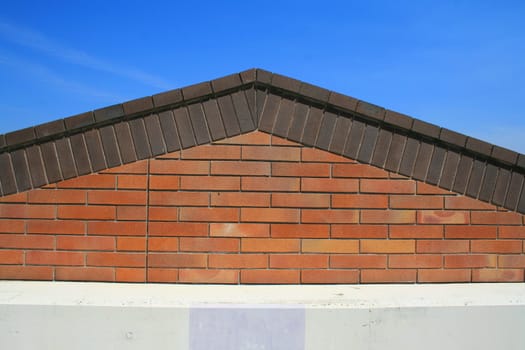 Brick roof peak over clear blue sky.
