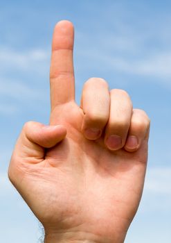 one. hand gesture with blue sky at background
