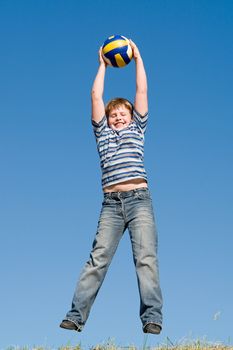 jumping boy with ball on a blue sky