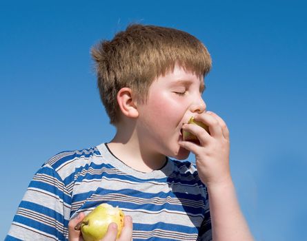 Difficult selection. Apple or pear? Boy with sky at background.