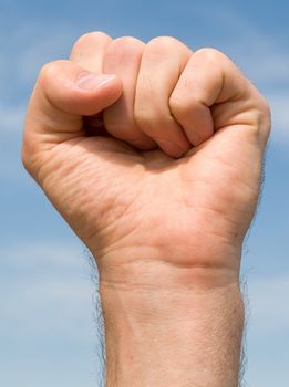 fist. Human hand on a blue sky