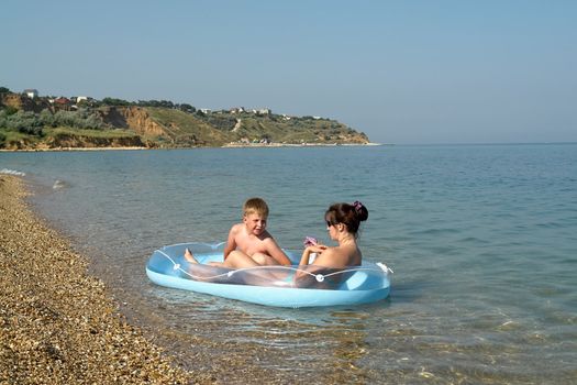 Mum and the son in an inflatable boat on the beach