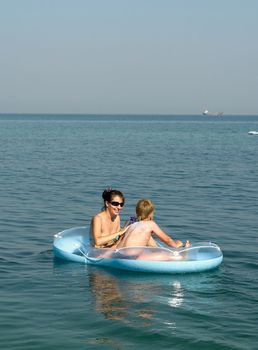 Mum and the son in an inflatable boat on the beach