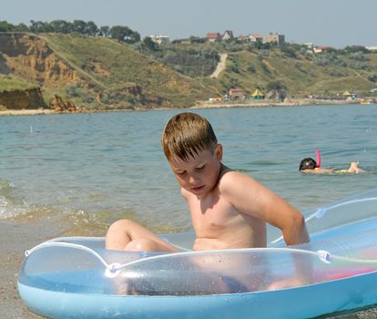 little boy in an inflatable boat on the beach