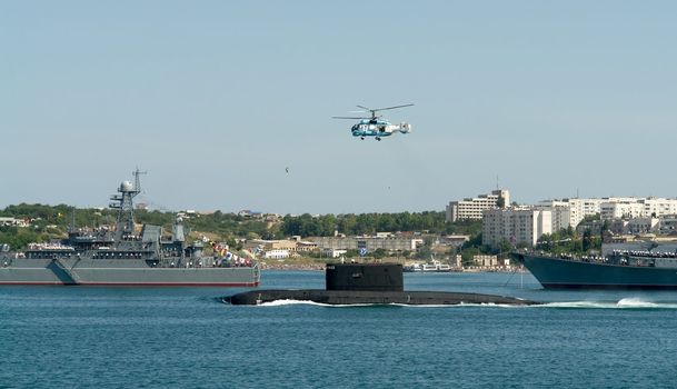 The military helicopter flies over a submarine