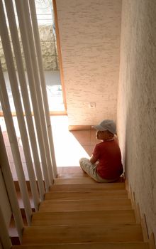 sad little boy sits at ladder steps