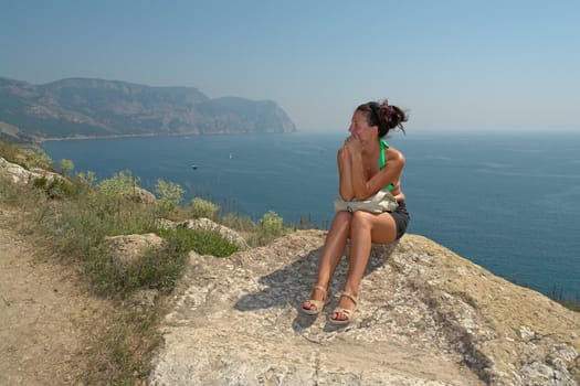 young beautiful woman against  mountains and the sea