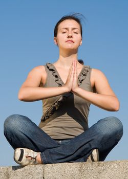 Meditation. The girl meditates with sky at background.