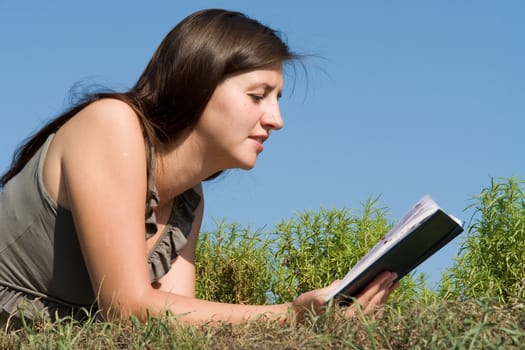 girl reads book with sky at background