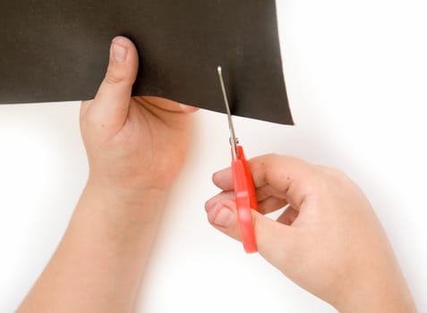 Children's hands with scissors cut a paper