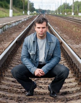 The young man sits on the railway