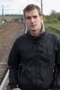 Cloudy day. The young man against the railway