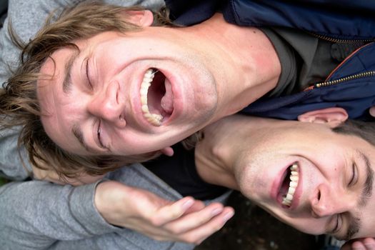 Laughter. Two laughing young men close up.