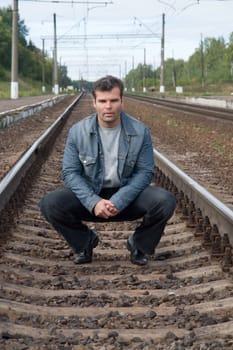The young man sits on the railway