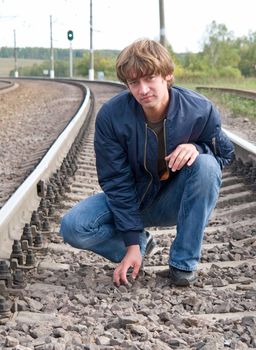 The young man sits on the railway