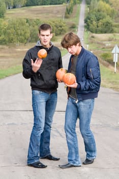 Two young dudes with pumpkins on road