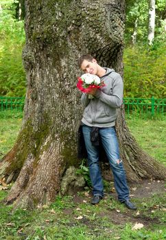 young man with flowers against a tree