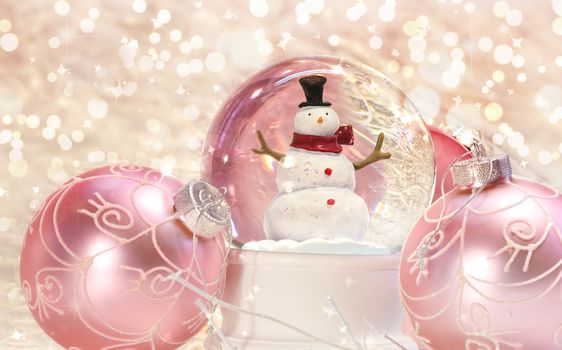 Snow globe with pink ornaments with sparkle background