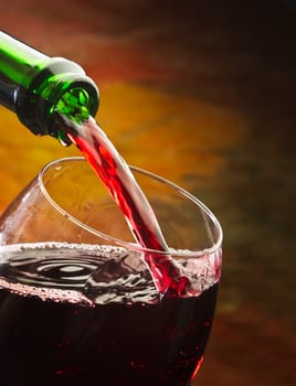 Wine pours into the glass of the bottle on a colored background