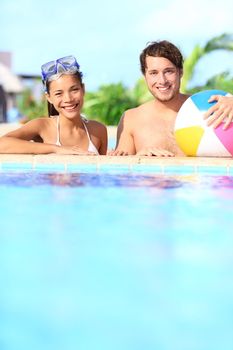 Holidays couple in pool having fun in sunny vacation resort under the sun. Young mixed race couple, Caucasian man, Asian woman.