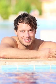 Man in swimming pool during vacation in holiday resort. Handsome male model enjoying sunny holidays under the sun. Young Caucasian man in his twenties.