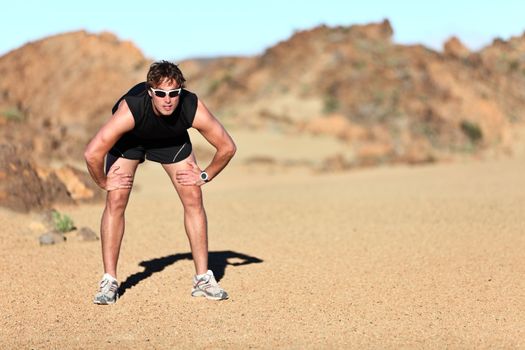 Workout outdoor runner. Man running taking a break from run outside in beautiful desert landscape. Fit young caucausian athletic model training for marathon outdoors.