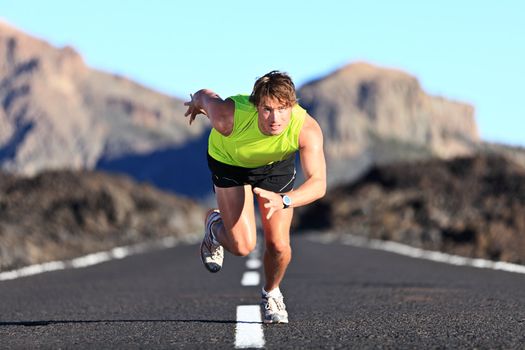 Sprinter. Man running on road at high speed in beautiful exotic mountain landscape. Male athlete runner in intense sprint during outdoor workout