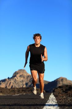 Running - male runner. Man sprinting during outdoor workout training session. Male caucasian athlete running on road in nature.