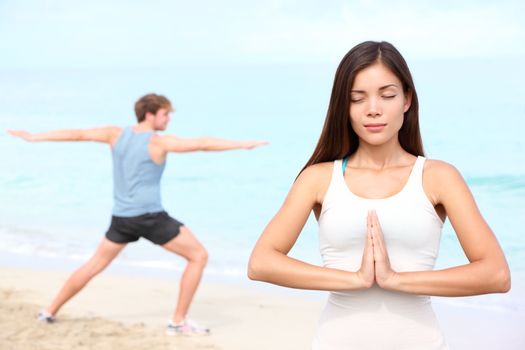 Yoga meditation couple meditating outdoor on beach. Young happy interracial couple during outdoor workout. Beautiful young Asian fitness woman and Caucasian man.