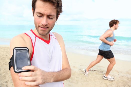 Running workout man with mp3 music player listening to music with mp3 player armband or smart mobile phone.