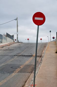 No entry red signs on sloped side street leading to motorway exit junction.