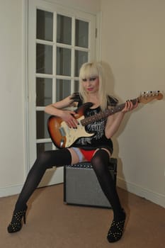 sexy girl sitting playing guitar