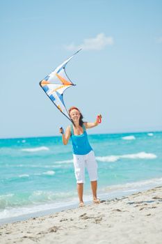 Young cute woman playing with a colorful kite on the tropical beach. Vertikal veiw
