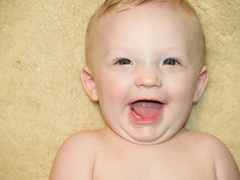 A very cute little infant smiling on a sheep skin blanket