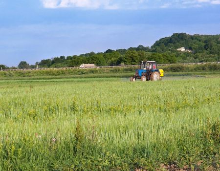 The tractor processes chemicals a field