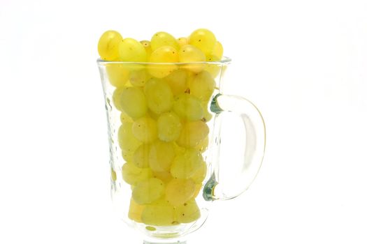 The glass cup full of yellow grapes