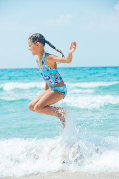 Beautiful girl jumping in the waves on the beach